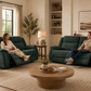 Man and a woman sit on dark teal reclining loveseats